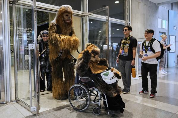 Star Wars fans wearing costumes of Chewbacca, left, and Widdle Warrick pose for a photo during a fan convention called the Star Wars Celebration in Chiba, near Tokyo, Friday, April 18, 2025. (AP Photo/Hiro Komae)