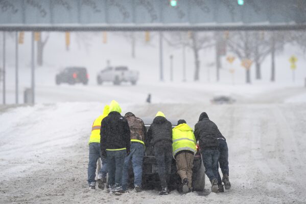 FILE - People help a driver out after his rear-wheel drive vehicle got stranded after a winter storm in Nashville, Tenn., Jan. 15, 2024. While the U.S. is shivering through bone-chilling cold, most of the rest of world is feeling unusually warm weather. Scientists Tuesday, Jan. 16, say that fits with what climate change is doing to Earth. (Denny Simmons/The Tennessean via AP)