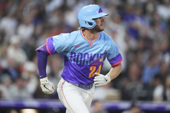 Colorado Rockies' Ryan McMahon follows the flight of his double that drove in two runs off New York Yankees relief pitcher Tim Hill in the fifth inning of a baseball game Friday, May 23, 2025, in Denver. (AP Photo/David Zalubowski)