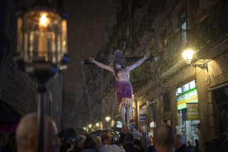 Worshippers carry an image of the Holy Christ of the Blood while it rains, during a procession through the streets of downtown Barcelona, Spain, Saturday, March 9, 2024. Preceded by nine days of prayers and emulating a documented historical tradition dating back five hundred years, worshippers requested rain as Catalonia last month declared drought emergency for the area of around 6 million people including the city of Barcelona. (AP Photo/Emilio Morenatti)