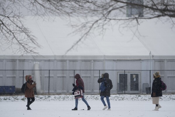 ARCHIVO - Varias personas caminan por un campo deportivo nevado frente a un albergue para migrantes, el viernes 19 de enero de 2024, en la Isla Randall de Nueva York. (AP Foto/Seth Wenig, Archivo)