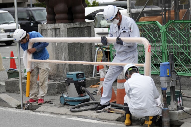 İşçiler, 30 Nisan 2024 Salı günü Japonya'nın merkezindeki Yamanashi Eyaleti, Fujikawaguchiko kasabasındaki bir Lawson mağazasının yakınında barikat kurdu.  (AP Fotoğrafı/Eugene Hoshiko)