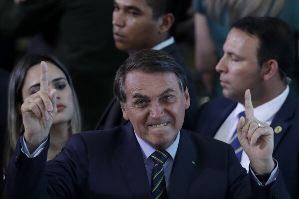 Brazil's President Jair Bolsonaro gestures during an event with young Venezuelan migrants at the Planalto Presidential Palace in Brasilia, Brazil, Thursday, Jan. 16, 2020. According to the UNHCR there are around 180,000 Venezuelan refugees and migrants in the country, many of them arrived crossing the border  in the northern state of Roraima. (AP Photo/Eraldo Peres)