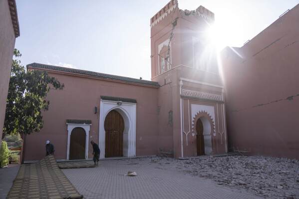 People set up rugs for prayer outside a mosque, that was damaged by the earthquake, in the town of Amizmiz, outside Marrakech, Morocco, Thursday, Sept. 14, 2023. (AP Photo/Mosa'ab Elshamy)