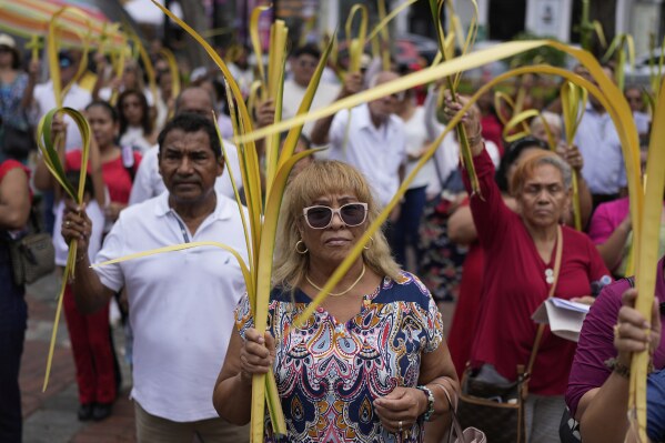 Faithful hold up palm fronds outside the Metropolitan Cathedral Basilica of Santa Maria before a Palm Sunday Mass in Panama City, Sunday, April 13, 2025. (AP Photo/Matias Delacroix)