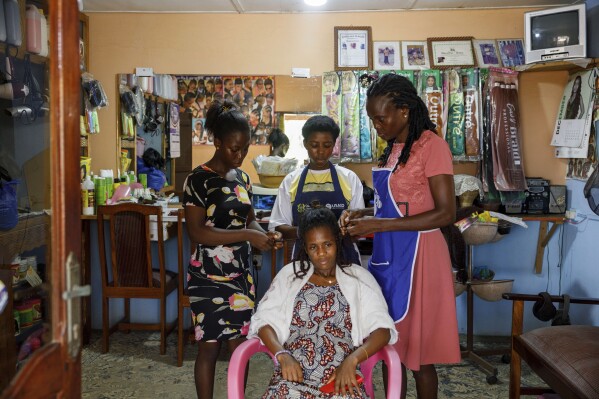 Afeli Bernice Adzo, left, and her Aunt Makafui Atayi work on a customer's hair in a shop in their family home in one of the rooms which is on the brink of being destroyed by the sea in Avegadzi, Ghana, Tuesday, March 4, 2025 (AP Photo/Misper Apawu)