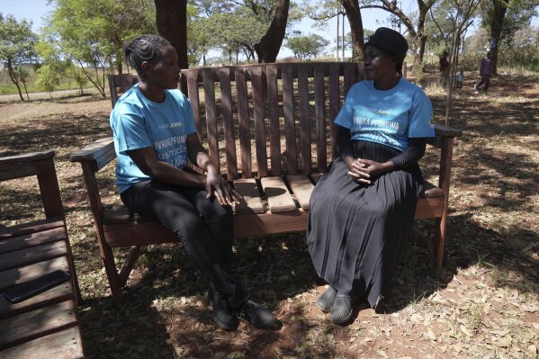Siridzayi Dzukwa, a grandmother, right, talks to a colleague while seated at a bench in Hatfcliffe on the outskirts of the capital Harare, Zimbabwe, Saturday, May 11,2024. In Zimbabwe, talk therapy involving park benches and a network of grandmothers has become a saving grace for people with mental health issues. Now the concept is being adopted in parts of the United States and elsewhere. (AP Photo/Tsvangirayi Mukwazhi)