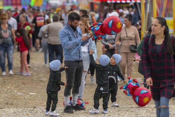 Children reach out for Spiderman balloons at a fair in Hagioaica, Romania, Saturday, Sept. 16, 2023. For many families in poorer areas of the country, Romania's autumn fairs, like the Titu Fair, are one of the very few still affordable entertainment events of the year. (AP Photo/Alexandru Dobre)