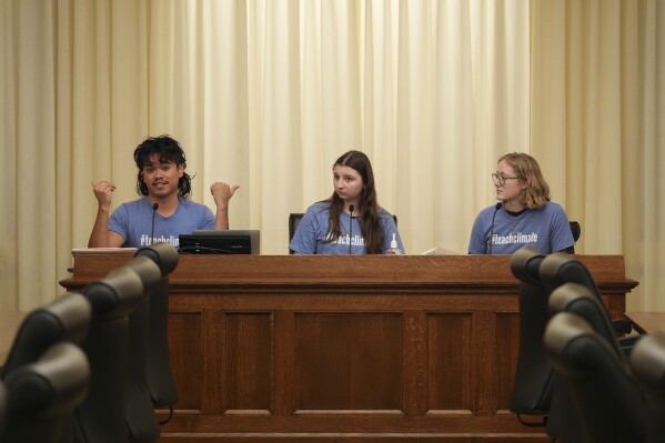 B Rosas, left, Lucia Everist, center, and Libby Kramer, of Climate Generation, speak to the Minnesota Youth Council, Tuesday, Feb. 27, 2024, in St. Paul, Minn. The advocates called on the council, a liaison between young people and state lawmakers, to support a bill requiring schools to teach more about climate change. (AP Photo/Abbie Parr)
