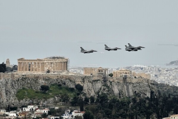 Greek F-16 fighter jets fly in front of the ancient Acropolis hill, during a military parade to commemorate the start of Greece's 1821 war of independence against the 400-year Ottoman rule, in Athens, on Tuesday, March 25, 2025. (AP Photo/Thanassis Stavrakis)