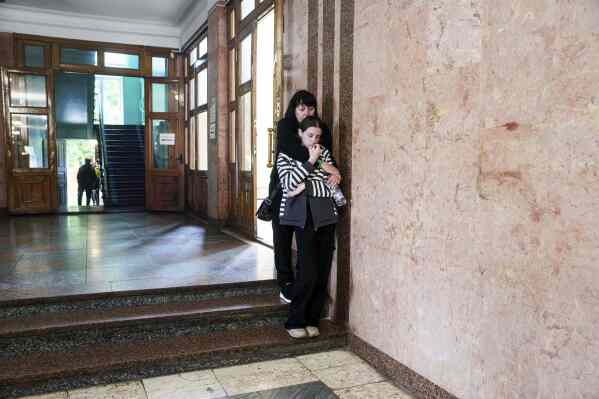 People cry during a funeral ceremony for Tamara Martyniuk, 8, Stanislav Martyniuk, 12, and Roman Martyniuk, 17, killed in a Russian strike on Sunday, in Korostyshiv, Zhytomyr region, Ukraine, Wednesday, May 28, 2025. (AP Photo/Evgeniy Maloletka)
