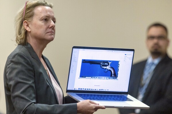 CORRECTION: REMOVES REFERENCE ABOUT OWNERSHIP OF GUN - Special prosecutor Kari Morrissey shows defense attorney Jason Bowles a picture of a firearmReed during Hannah Gutierrez-Reed trial at District Court, Monday, Feb. 26, 2024, in Santa Fe, N.M. Gutierrez-Reed is charged with involuntary manslaughter and tampering with evidence in the October 2021 death of cinematographer Halyna Hutchins during the filming of the Western “Rust”. (Luis Sánchez Saturno/Santa Fe New Mexican via AP, Pool)