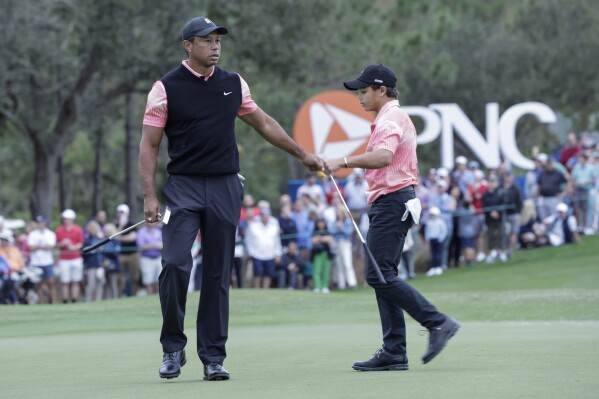 FILE - Tiger Woods, left, congratulates his son Charlie Woods, right, after finishing the 18th hole during the first round of the PNC Championship golf tournament Saturday, Dec. 17, 2022, in Orlando, Fla. Woods and his son are returning to play in this year's tournament for the fourth straight year. (AP Photo/Kevin Kolczynski, File)