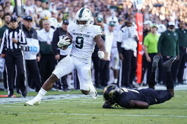 FILE - Michigan State running back Kenneth Walker III (9) breaks the tackle of Purdue cornerback Jamari Brown (7) on his way to a touchdown during the first half of an NCAA college football game in West Lafayette, Ind., Nov. 6, 2021. (AP Photo/Michael Conroy, File)