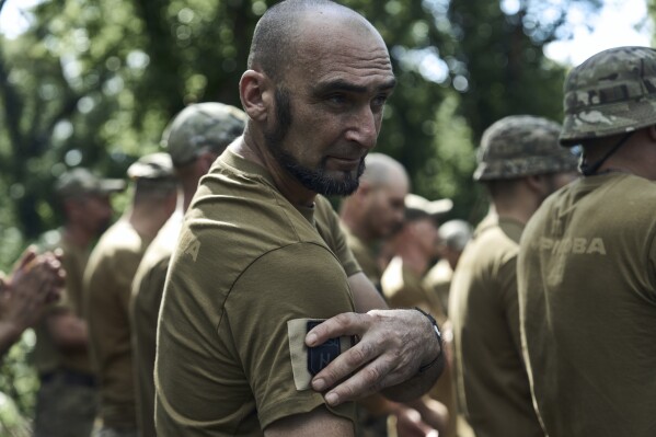 A soldier of Ukraine's 3rd Separate Assault Brigade attaches the brigade emblem on his T-shirt, near Bakhmut, the site of fierce battles with the Russian forces in the Donetsk region, Ukraine, Sunday, Sept. 3, 2023. (AP Photo/Libkos)