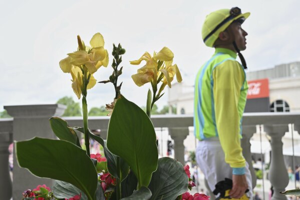 A jockey walks past flowers at Churchill Downs before the 151st running of the Kentucky Oaks horse race Friday, May 2, 2025, in Louisville, Ky. (AP Photo/Jon Cherry)