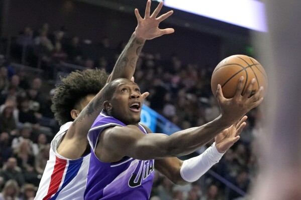 ARCHIVO - El guardia de los Utah Jazz, Kris Dunn (11), va a la canasta mientras el delantero de los Detroit Pistons, Isaiah Livers (12), defiende durante la primera mitad de un partido de baloncesto de la NBA el miércoles 3 de enero de 2024 en Salt Lake City.  Ningún equipo de la NBA ha disfrutado de mayor éxito en enero hasta ahora que Utah.  Un factor que ha contribuido silenciosamente a este aumento ha sido el juego constante del base Kris Dunn.  (Foto AP/Rick Bowmer, archivo)