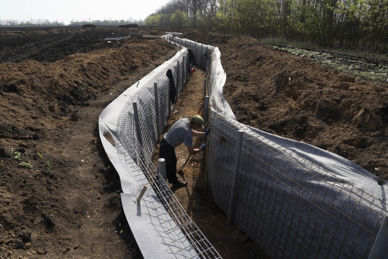 A worker constructs new defensive positions close to the Russian border in Kharkiv region, Ukraine, on Wednesday, April 17, 2024. (AP Photo/Evgeniy Maloletka)