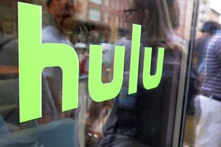 FILE - This June 27, 2015, file photo, shows the Hulu logo on a window at the Milk Studios space in New York. Disney has struck a deal with Comcast that gives it full control of streaming service Hulu. The companies said Tuesday, May 14, 2019, that as early as January 2024 Comcast can require Disney to buy NBCUniversal’s 33% interest in Hulu and Disney can require NBCUniversal to sell that stake to Disney for its fair market value at that future time. (AP Photo/Dan Goodman, File)