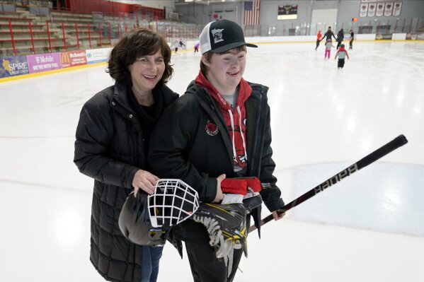 Suzy Lindeberg poses with her 20-year-old son John on a hockey rink, Tuesday, Feb. 9, 2021 in Stillwater, Minn. John, who has Down Syndrome, can't spend as much time at the rink as he used to since he is at a higher risk for hospitalization or death if he caught COVID-19, but his mother and other advocates worry that the state of Minnesota has placed people with disabilities too far down the priority list.  (AP Photo/Jim Mone)