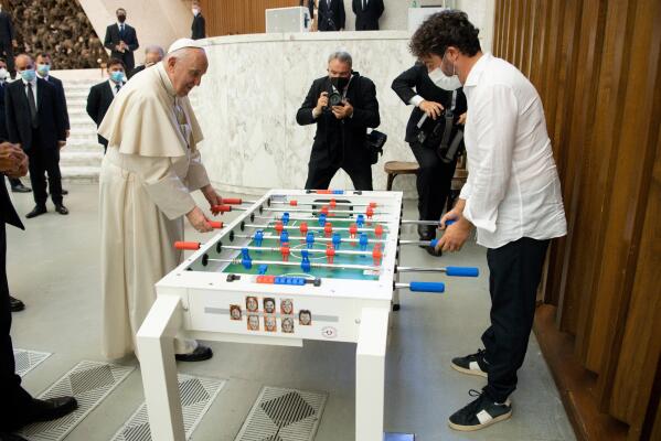 Pope Francis plays with Natale Tonini, president of Sport Toscana Calcio Balilla association, at the end of the weekly general audience, Wednesday, Aug.18. 2021. Francis played a round on the table that was presented to him  by representatives of a the association, that created a special Foosball table designed to be inclusive, for people with physical disabilities, to encourage their participation in sport. (Vatican Media via AP)