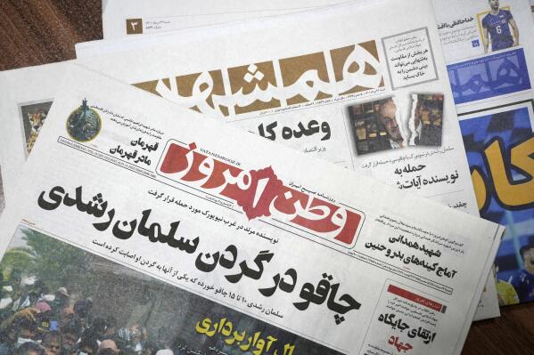 The front pages of the Aug. 13 edition of the Iranian newspapers, Vatan-e Emrooz, front, with title reading in Farsi: "Knife in the neck of Salman Rushdie," and Hamshahri, rear, with title: "Attack on writer of Satanic Verses," are pictured in Tehran Saturday, Aug. 13, 2022. Rushdie, whose novel “The Satanic Verses” drew death threats from Iran’s leader in the 1980s, was stabbed in the neck and abdomen Friday by a man who rushed the stage as the author was about to give a lecture in western New York. (AP Photo/Vahid Salemi)
