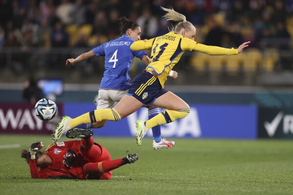 Italy's goalkeeper Francesca Durante, on the pitch, Italy's Lucia Di Guglielmo and Sweden's Stina Blackstenius, right, compete for the ball during the Women's World Cup Group G soccer match between Sweden and Italy in Wellington, New Zealand, Saturday, July 29, 2023. (AP Photo/Alysa Rubin)
