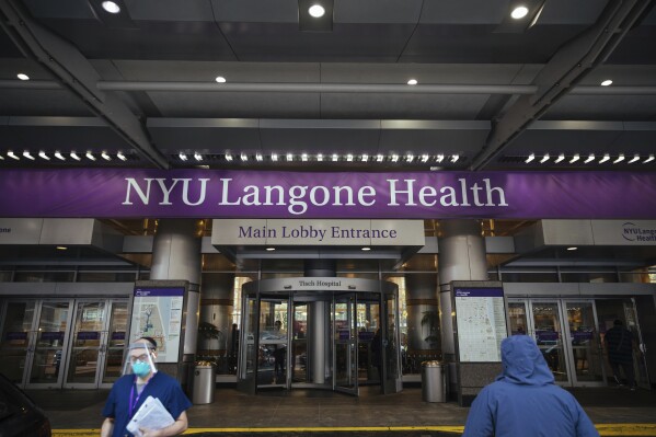 FILE - Health care workers walk in and out of the entrance at NYU-Langone Hospital on Monday, Dec. 14, 2020, in New York. A nurse was fired by the hospital after she referred to Israel's war in Gaza as "genocide" during a speech accepting an award. Labor and delivery nurse Hesen Jabr, who is Palestinian American, was being honored by NYU Langone Health for her compassion in caring for mothers who had lost babies when she drew a link between her work and the suffering of mothers in Gaza. (AP Photo/Kevin Hagen, File)