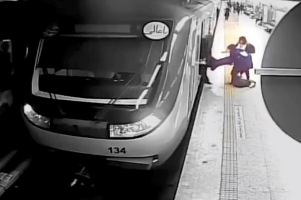 In this image from surveillance video aired by Iranian state television, women pull 16-year-old Armita Geravand from a train car on the Tehran Metro in Tehran, Iran, Sunday, Oct. 1, 2023. The mysterious injury suffered by Geravand not wearing a headscarf while boarding a Metro train in Iran's capital has reignited anger just after the one-year anniversary of the death of Mahsa Amini and the nationwide protests it sparked. (AP Photo/Iranian state television)