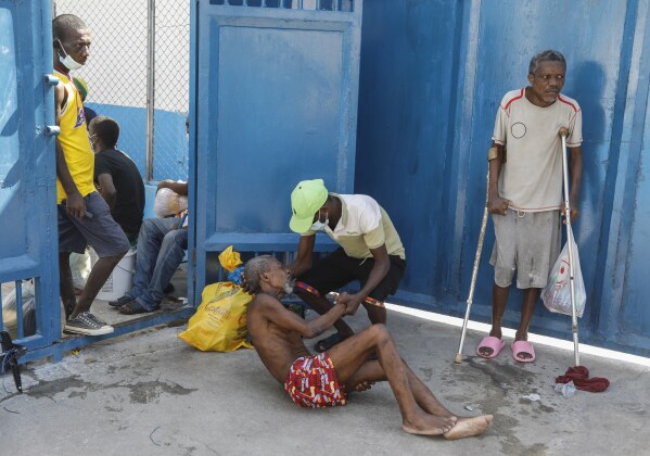 An inmate helps another prisoner inside the National Penitentiary in Port-au-Prince, Haiti, Sunday, March 3, 2024. Hundreds of inmates fled Haiti's main prison after armed gangs stormed the facility overnight. (AP Photo/Odelyn Joseph)