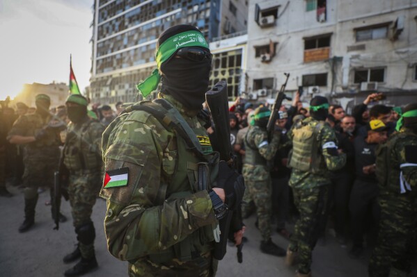 fighters from the qassam brigades, the military wing of hamas, control the crowd as red cross vehicles come to collect israeli hostages under a ceasefire agreement between israel and hamas, in gaza city, jan. 19, 2025. (ap photo/abed hajjar, file)