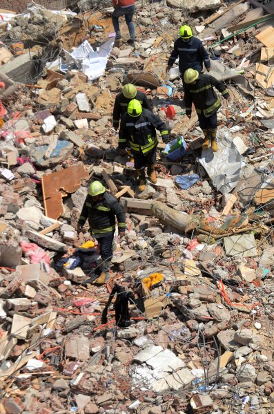 Rescuers look for victims on the rubble of a collapsed apartment building in the el-Salam neighborhood, in Cairo, Egypt, Saturday, March 27, 2021.  A nine-story apartment building collapsed in the Egyptian capital early Saturday, killing at several and injuring about two dozen others, an official said. (AP Photo/Tarek wajeh)
