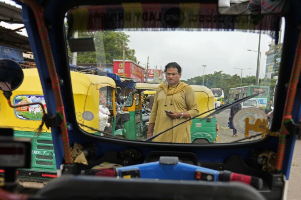 Preethi, a 38-year-old transgender woman who uses only her first name, looks for customers to ferry in her electric auto rickshaw on a busy street in Bengaluru, India, Wednesday, July 12, 2023. She's now one of millions of electric vehicle owners in India, but one of very few to have received an EV through a charitable donation. (AP Photo/Aijaz Rahi)