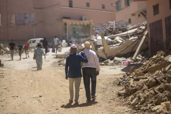 Gente camina entre los escombros causados por el terremoto, en la ciudad de Amizmiz, cerca de Marrakech, Marruecos, el domingo 10 de septiembre de 2023. (Foto AP/Mosa'ab Elshamy)