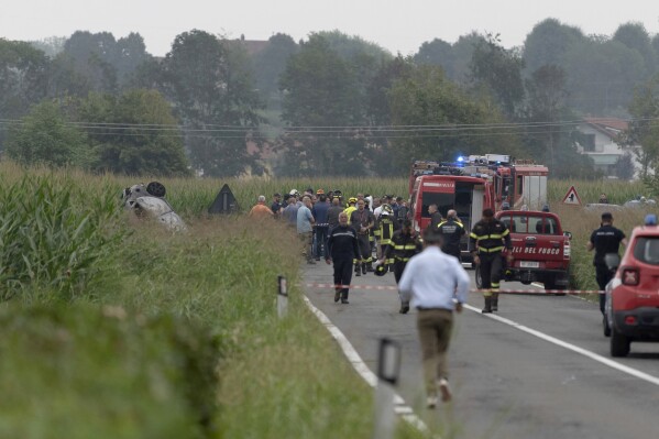The debris of a burnt car is seen at left as firefighters seal off the area where an aircraft of the Italian acrobatic air team the Frecce Tricolori crashed during a practice run outside the northern city of Turin, Italy, Saturday, Sept. 16, 2023. The plane or parts of the plane reportedly struck a car carrying a family, killing a 5-year-old girl. A 9-year-old and the parents were being treated for burns, according to an Italian news agency. (Matteo Secci/LaPresse via AP)
