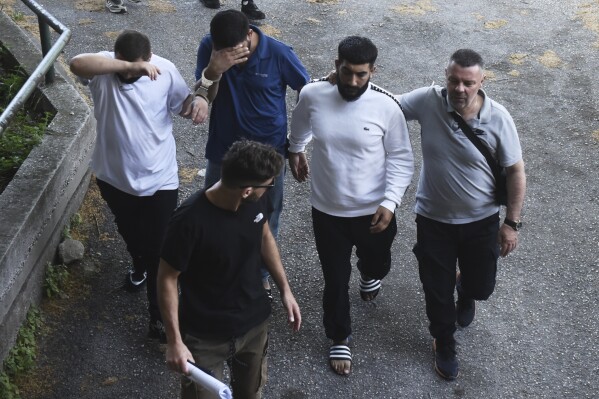 Three of the five suspect members of criminal gangs, based in Turkey, are escorted by police for an arraignment hearing in the northern port city of Thessaloniki, Greece, Thursday, May 29, 2025. (AP Photo/Giannis Papanikos)