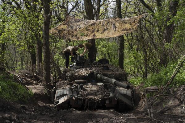 Ukrainian servicemen install a machine gun on the tank during the repair works after fighting against Russian forces in Donetsk region, eastern Ukraine, Wednesday, April 27, 2022. (AP Photo/Evgeniy Maloletka)