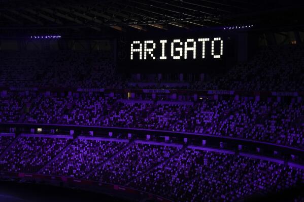 FILE - "Ariagato" is displayed at the end of the closing ceremony in the Olympic Stadium at the 2020 Summer Olympics, Sunday, Aug. 8, 2021, in Tokyo, Japan. The Tokyo Olympics survived the COVID-19 postponement, soaring expenses and some public opposition. A year later, the costs and benefits are as difficult to untangle as the Games were to pull off.   (AP Photo/Vincent Thian, File)