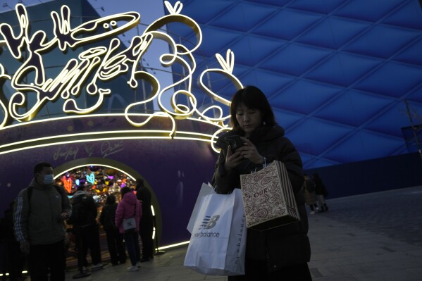 Shoppers visit a popular mall in Beijing, Sunday, Dec. 15, 2024. (AP Photo/Ng Han Guan)