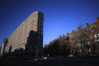 FILE - In this Jan. 17, 2019 file photo, Boston University's Myles Standish Hall dormitory, left, is partially covered in shadow in Boston. THe Massachusett Tribe at Ponkapoag is calling on BU to change the name of the dorm that honors Myles Standish, the military leader of the Pilgrims. The tribe says Myles Standish Hall should be renamed Wituwamat Memorial Hall after a leading Native American figure massacred with other tribal members by Plymouth Colony settlers in 1623. (Lane Turner/The Boston Globe via AP, File)