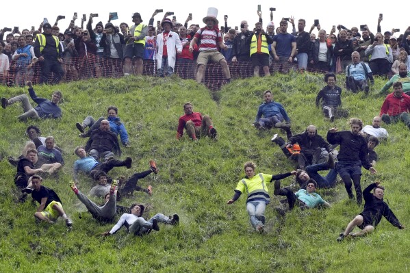 Participants take part in the annual cheese rolling at Cooper's Hill in Brockworth, England, Monday, May 27, 2024. The traditional event attracts people from around the globe who come to chase a 7lb Double Gloucester cheese down the steep Coopers Hill. (Jacob King/PA via AP)