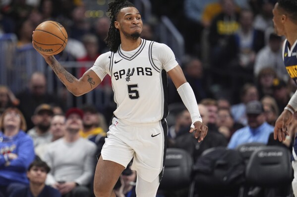 San Antonio Spurs guard Stephon Castle, left, throws a pass over Denver Nuggets guard Russell Westbrook in the second half of an NBA basketball game Wednesday, April 2, 2025, in Denver. (AP Photo/David Zalubowski, file)