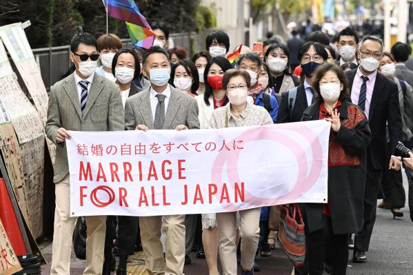 Plaintiffs and supporters walk to the Tokyo district court in Tokyo, Japan, Wednesday, Nov. 30, 2022. Japan's lack of law to protect the right of same-sex couples to marry and become families is unconstitutional, the Tokyo District Court ruled Wednesday in a closely-watched case in a country still largely bound by traditional gender roles and family values.(Kyodo News via AP)