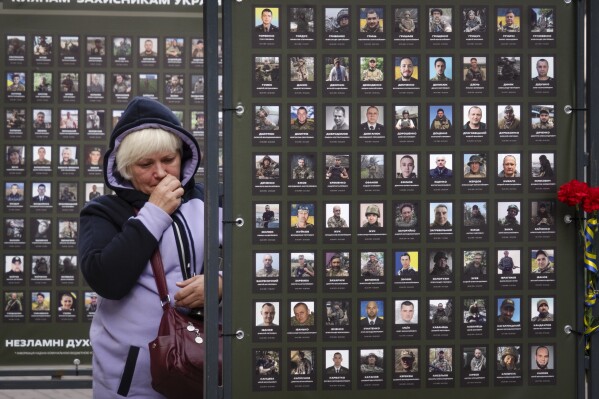 Liudmila Melnik wipes tears as she looks at a photo of her husband Oleksandr, who was killed in a battle with the Russian troops, near the City Hall in Kyiv, Ukraine, Wednesday, Oct. 4, 2023. Over one thousand photos of Kyiv residents killed in the war have been displayed in front of the City Hall. (AP Photo/Efrem Lukatsky)