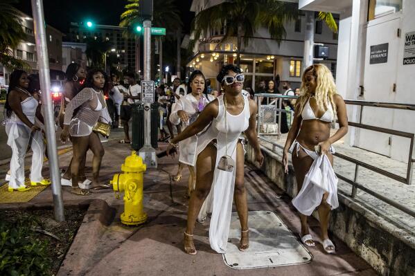 A group of women twerk on Washington Avenue early Saturday night before the midnight curfew imposed by the City of Miami Beach, Fla., Saturday March 26, 2022. Miami Beach officials have spent recent years trying to control the raucous crowds, public drinking and growing violence associated with the city's world-famous South Beach neighborhood during spring break. (Pedro Portal/Miami Herald via AP)