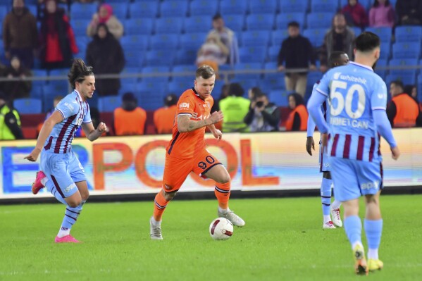 Istanbul Basaksehir's Eden Karzev, center, fights for the ball with Trabzon's Enis Destan, left, during a Turkish Super Lig soccer match between Istanbul Basaksehir and Trabzon, at Papara Park stadium in Trabzon, Turkey, Saturday, Dec. 23, 2023. Turkey soccer club Basaksehir says it's ended its contract with Israeli player Karzev following a disciplinary probe of his social media post calling for the release of hostages held in Gaza by the Hamas militant group it was announced on Thursday, Jan. 18, 2024. (Serkan Hacioglu/Dia images via AP)