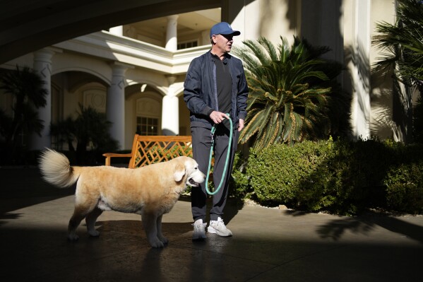 Kirk Herbstreit stands with his dog Ben outside of his hotel Thursday, Dec. 14, 2023, in Las Vegas. Herbstreit, a sportscaster with Amazon Prime, ESPN and ABC, brings Ben along with him on work trips. (AP Photo/John Locher)