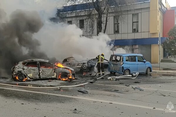 FILE - In this photo taken from video released by Russian Emergency Situations Ministry Telegram channel on Dec. 30, 2023, firefighters extinguish burning cars after shelling in Belgorod, Russia. The attack in the city near the border with Ukraine killed 25 people and injured 109, dealing a heavy blow to President Vladimir Putin's attempts to reassure his countrymen that their lives have been largely unchanged by the nearly two-year military operation. (Russia Emergency Situations Ministry Telegram channel via AP, File)