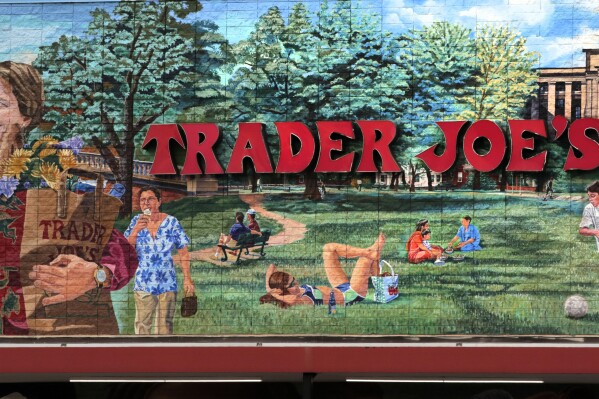 FILE - In this Aug. 13, 2019, file photo, Trader Joe's logo hangs on a mural at it's market in Cambridge, Mass. Trader Joe's is recalling a broccoli cheddar soup that may contain insects and cooked falafel over possible rocks, about one week after the grocery chain recalled two cookie products over similar concerns. The soup recall impacts Trader Joe’s Unexpected Broccoli Cheddar Soup with “Use By” dates ranging from July 18 to September 15 of this year, according to a Thursday, July 27, 2023 announcement from the company. (AP Photo/Charles Krupa)