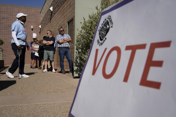 FILE - People wait in line to vote at a polling place on June 14, 2022, in Las Vegas. Six Republicans who have been indicted on charges that they submitted paperwork to Congress falsely declaring Donald Trump the winner of the Western swing state in 2020 are scheduled to make their initial court appearances Monday. (AP Photo/John Locher, File)
